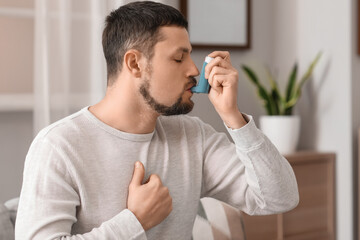 Fototapeta na wymiar Sick man using inhaler at home