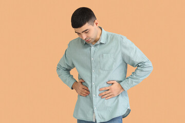 Young man with appendicitis on beige background