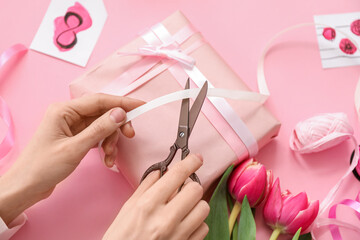 Woman making present for International Women's Day celebration on pink background, closeup