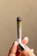 Female model holding a lit joint upright