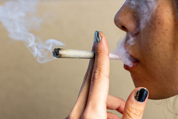 Female model smoking a lit joint with smoke all around