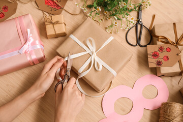 Woman packing presents for International Women's Day celebration on wooden background