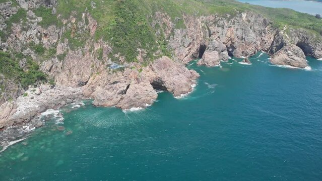 Helicopter hovering above water, creating ripples in the sea water. Hong Kong. Aerial view with shadow. Sea cliffs. Summer sunny day. Asia. 