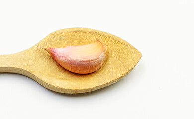 A wooden spoon for cooking, containing a garlic