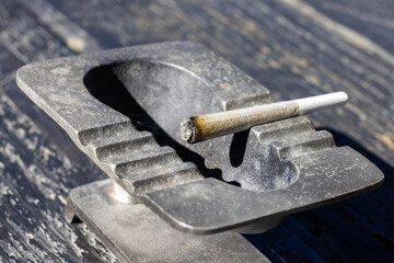 Close up on a lit joint sitting in an ashtray 