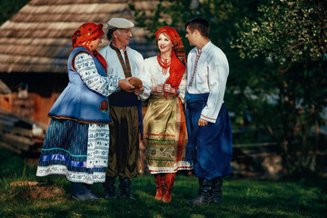 happy ukrainian family in traditional costumes at old village background