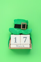Leprechaun hat and calendar with date of St. Patrick's Day on green background