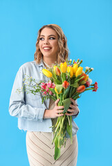 Beautiful happy young woman with bouquet of tulips on light blue background