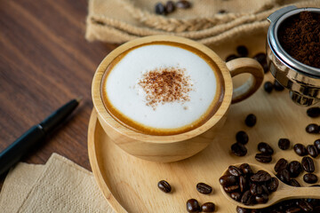 Hot coffee espresso latte with milk froth foam in wood cup. barista pouring milk liquid froth foam to wood cup of espresso for make creamy cappuccino hot drink.