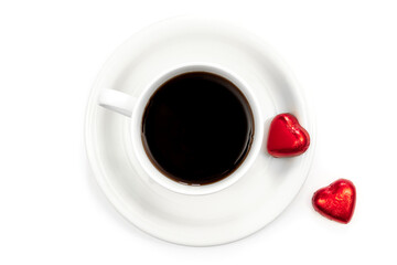 Cup of coffee and heart shaped chocolates on a white background, flat lay.
