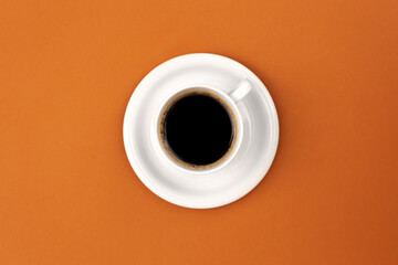 Coffee cup and saucer on brown background, flat lay.