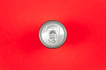 Aluminum drink or beverage can with pull ring on a red background, flat lay.
