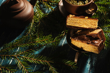 Christmas- still life with a piece of cake and morning tea. Fir tree branches- breakfast on a dark background