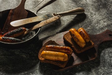 Still life fried sausages in a cast-iron pan on a dark background