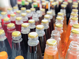 Selective focus. Glass Bottles and colored softdrink with metal cap.