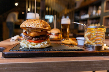Delicious homemade hamburger and beer, onion ring and french fries on the table on wooden background.