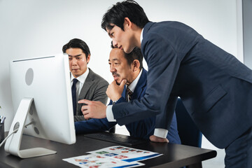 パソコン画面を見ながら会議するビジネスマンのグループ