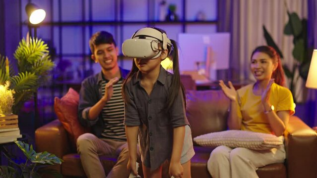 Girl 6 y.o. experiencing VR headset game at home.daughter wearing VR eyeglasses on the metaverse,Child playing metaverse gaming gadget for virtual reality,goggles at home.Virtual technology concept.
