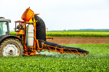 Obraz premium Tractor-applied herbicides, pesticides, and fungicides in wheat fields, farmer protecting crops from pests and diseases