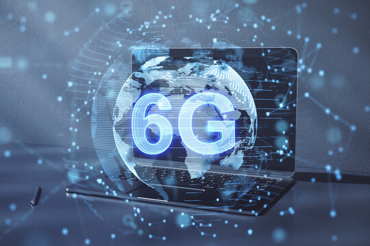 Close up of laptop with globe with 6g hologram on blurry background. Telecommunication and internet speed concept. Double exposure.