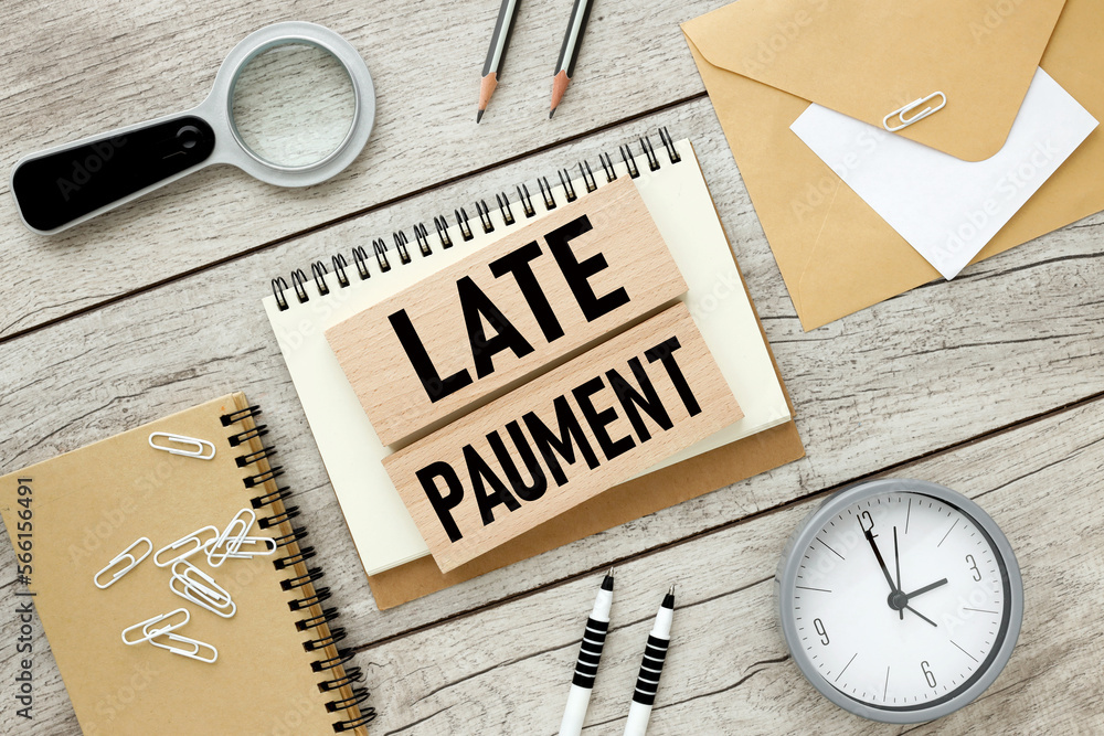 Poster late payment. business concept. two wooden blocks with text on an open notepad.