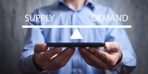 Man showing supply and demand word balance scales. Business concept