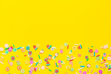 flat lay of colorful sprinkles over yellow background, festive decoration for banner, poster, flyer, card, postcard, cover, brochure, designers, copy space