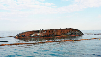 Sunken drowned tanker ship near the aground. Broken rusty ship on the shallow water.