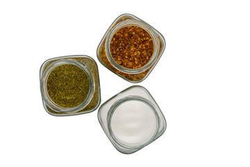 Three glass jars with spices, top view, isolated on white