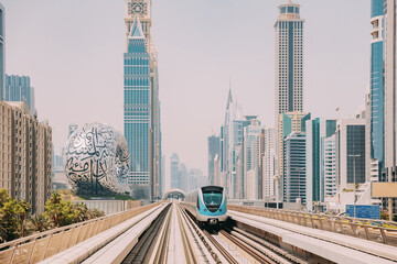 Fototapeta na wymiar Monorail Subway train rides among glass skyscrapers in Dubai. Traffic on street in Dubai. Museum of the Future in Dubai. Cityscape skyline. Urban background.