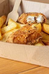 Fish and chips takeaway in a cardboard tray with a wooden fork. Biodegradable plastic free eco friendly takeaway container