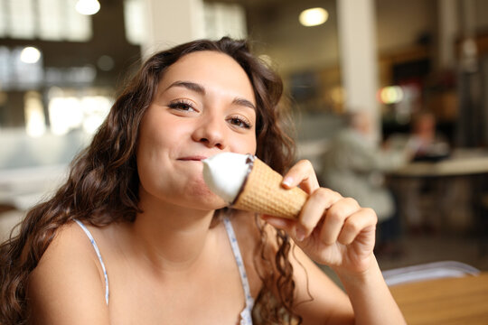 Happy woman eating ice cream looks at you