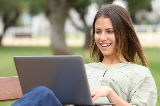 Happy teen using laptop in a park