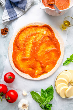 Flay lay of pizza dough with tomato sauce and ingredients kept on table