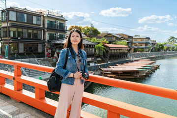smiling asian Japanese lady traveler looking at beautiful scenery on red uji bashi bridge over uji...