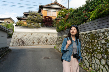 curious asian Japanese woman traveler standing on a slope and looking into distance while exploring...