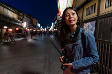 Obraz na płótnie Canvas smiling asian Japanese girl visitor looking into space with curiosity while visiting geisha district on hanamikoji street in gion Kyoto japan at nighttime