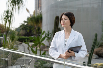 portrait of beautiful smiling asian Chinese woman plant biologist holding computer pad and looking...