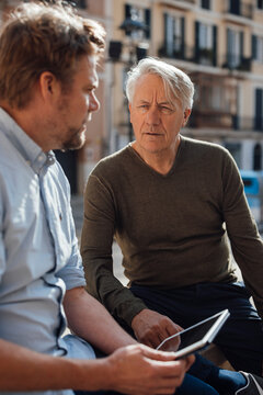 Mature man holding tablet PC and talking with father