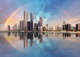 Rainbow over Abu Dhabi skyline with reflection in sea, United Arab Emirates - panorama