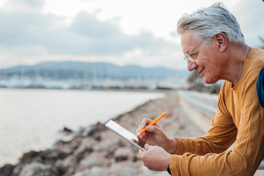 Smiling senior man using tablet PC with digitized pen