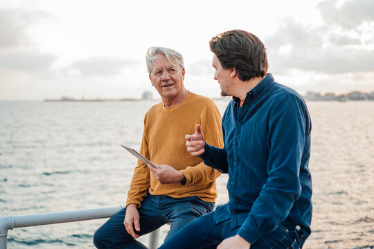 Father and son having discussion sitting in front of sea