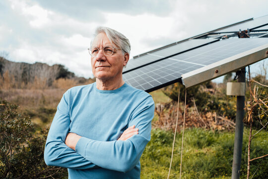 Senior Man Wearing Eyeglasses Standing In Front Of Solar Panels