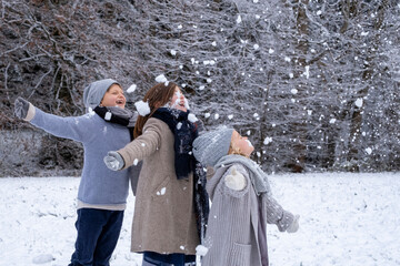 Cheerful brother and sisters in warm clothing enjoying snow
