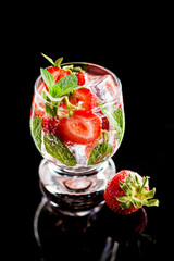 Infused water with strawberry, ice, mint on black background