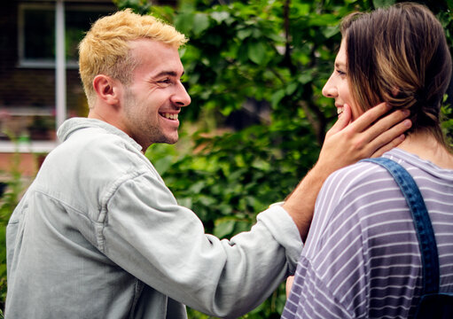 Happy boyfriend touching cheek of girlfriend in back yard