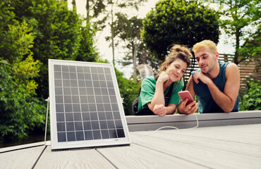 Couple sharing smart phone being charged by solar panel