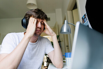 Tired freelancer sitting in front of laptop at home office