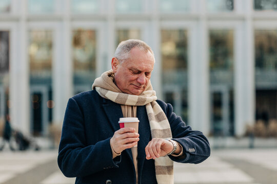 Senior Man Checking Time Holding Disposable Drink Cup