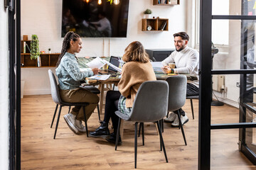 Business colleagues sitting with charts and discussing at table in office